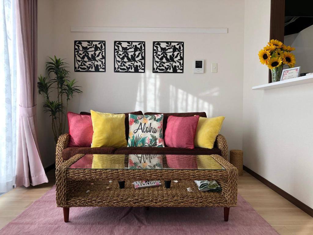 a wicker couch with colorful pillows in a living room at TerraceRin YN23 in Tomigusuku