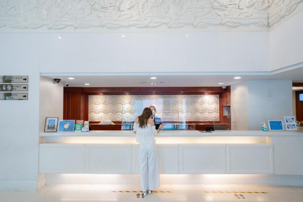 A bright hotel reception desk beneath an ornate white ceiling feature.