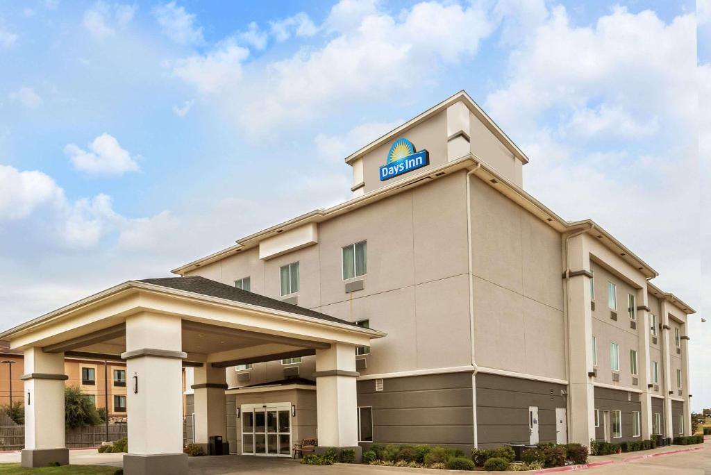 a hotel building with a sign on top of it at Days Inn & Suites by Wyndham Mineral Wells in Mineral Wells