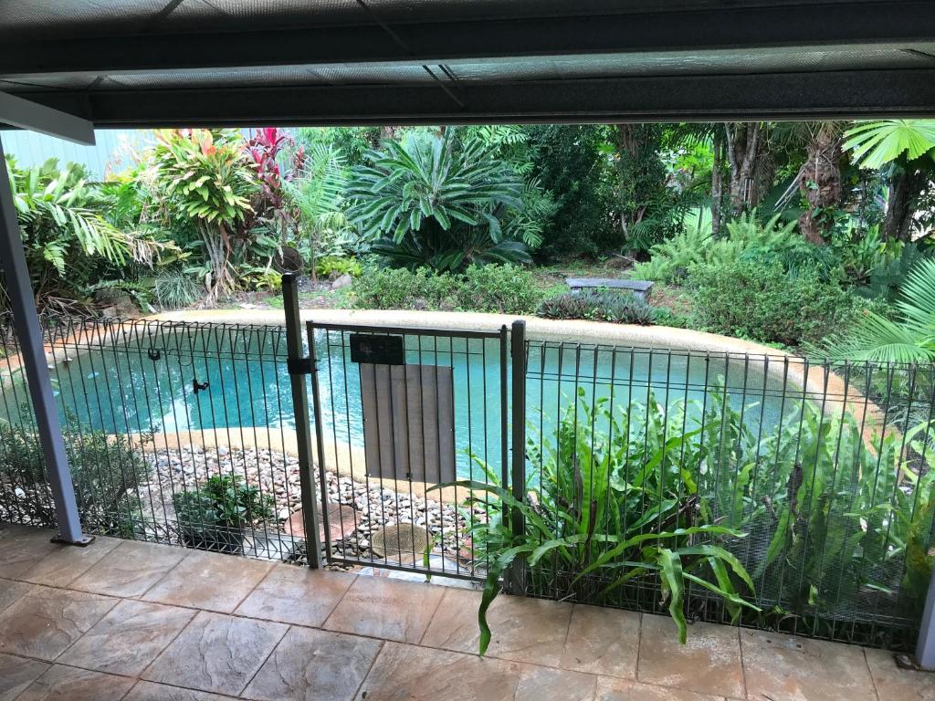 a fence around a swimming pool in a garden at Royal Palm Cottage, Entire two bedroom 2 bathroom house with Pool in Mission Beach