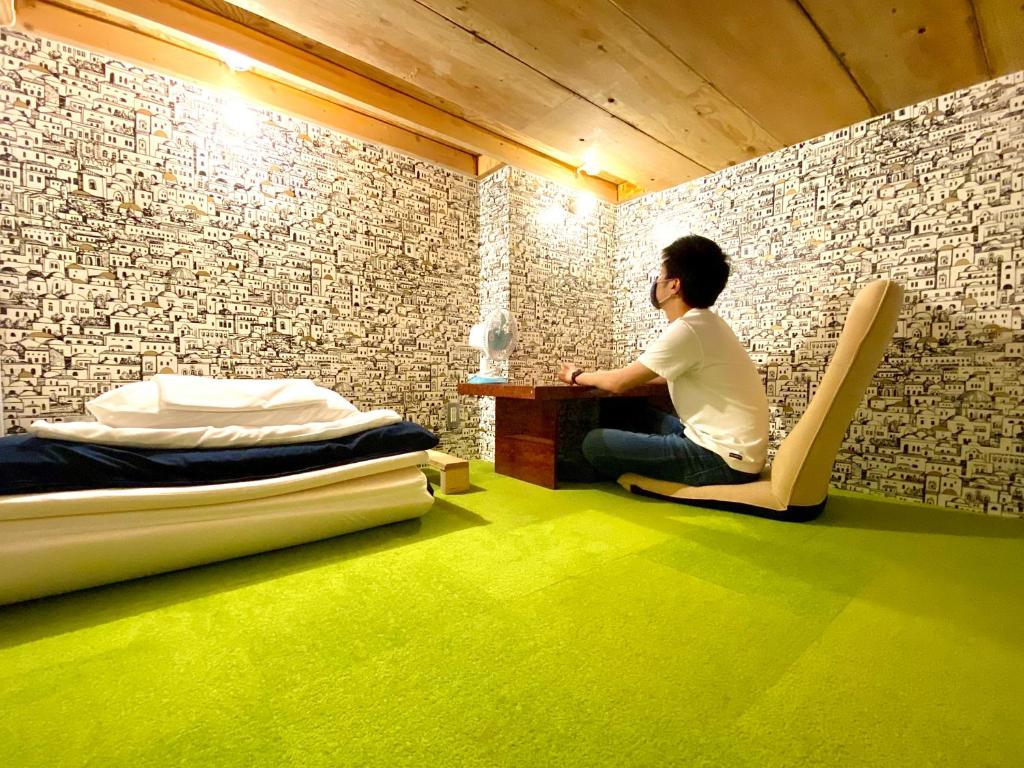 a man sitting at a desk in a room at Guest House MARUYA in Atami