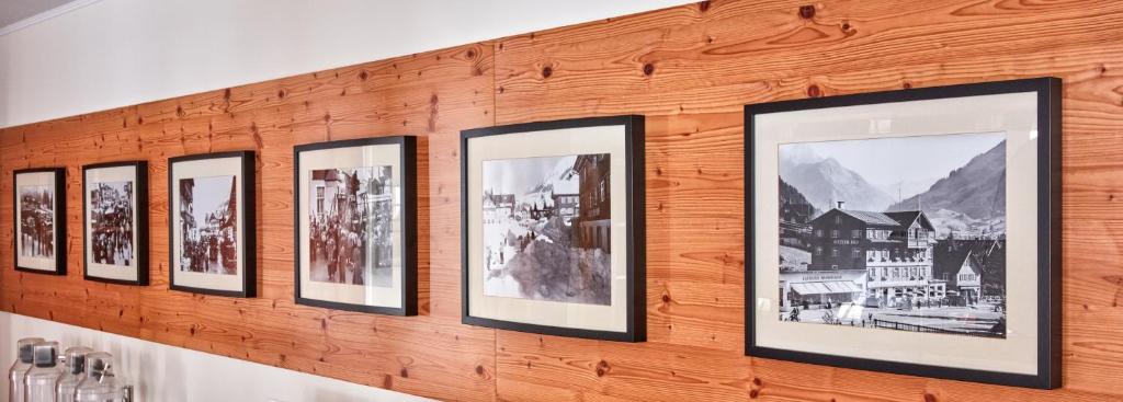 eine Reihe gerahmter Bilder an einer Holzwand in der Unterkunft Hotel Riezler Hof in Riezlern