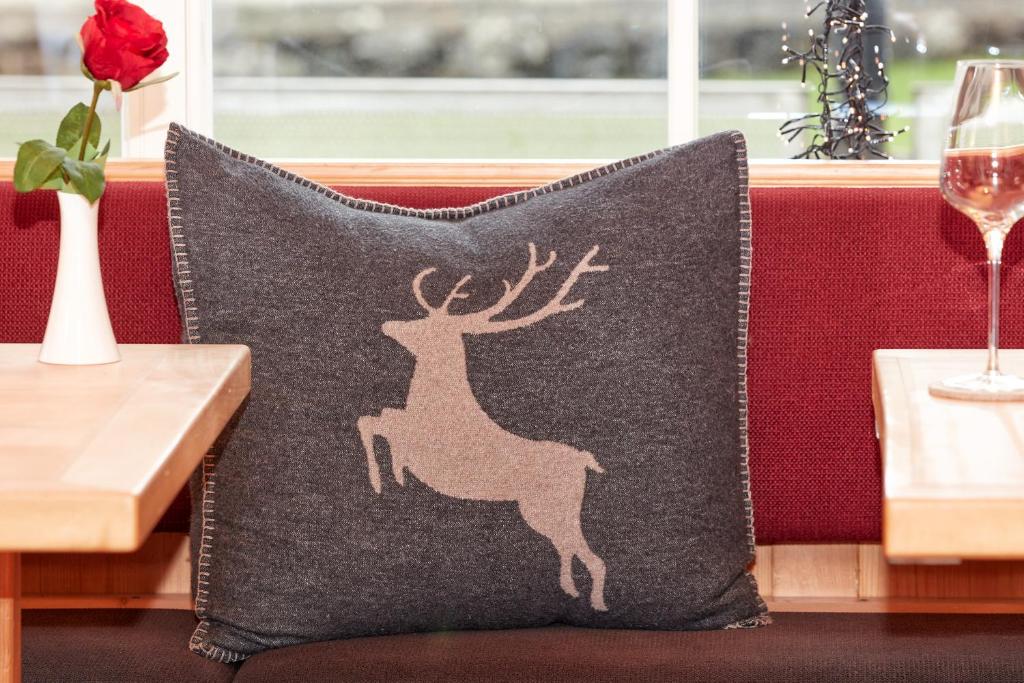 ein Kissen mit einem Hirsch-Applikat auf einer Couch in der Unterkunft Hotel Riezler Hof in Riezlern