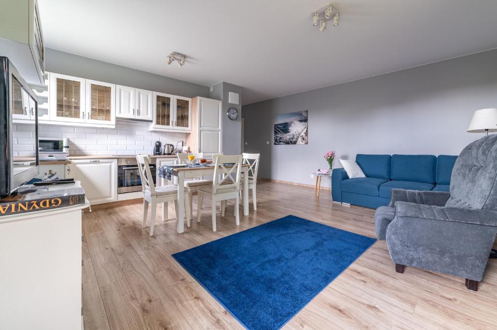 a living room with a blue couch and a table at Nautical Sea Apartment in Gdynia