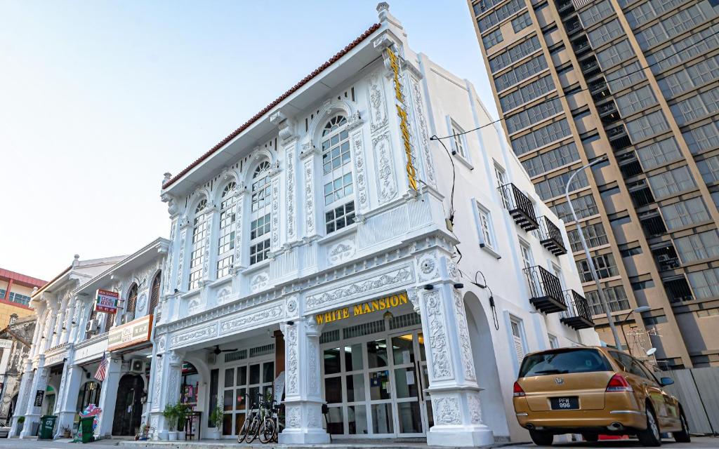un edificio blanco con un coche aparcado delante de él en White Mansion Penang, en George Town