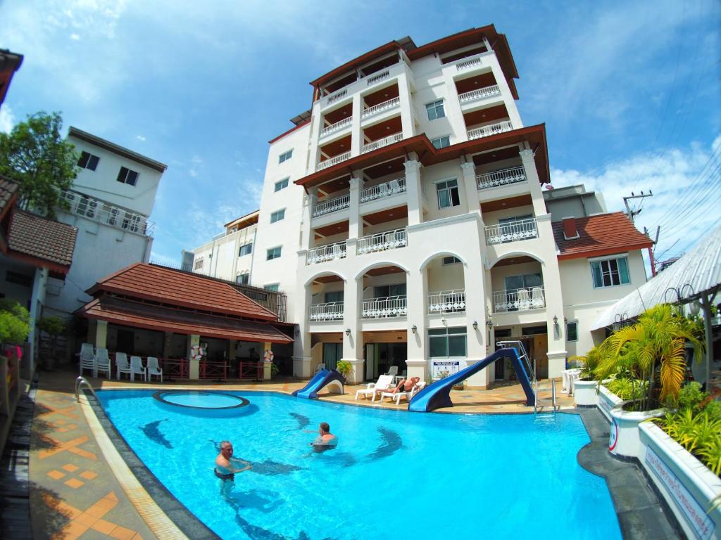 een zwembad voor een gebouw waar mensen in spelen bij Jed Pee Nong Hotel โรงแรมเจ็ดพี่น้อง in Hua Hin