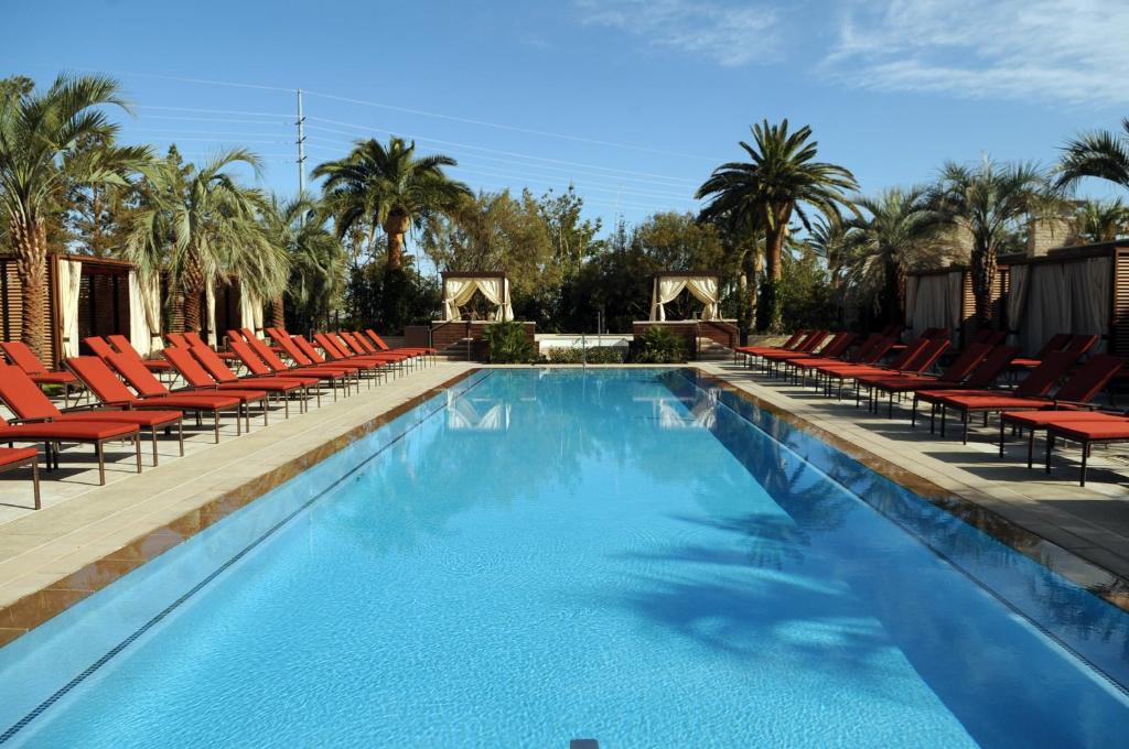 einen großen Pool mit roten Stühlen und Palmen in der Unterkunft M Resort Spa &amp; Casino in Las Vegas
