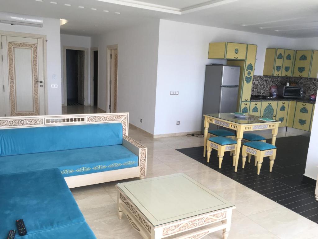 a living room with a blue couch and a table at Arabesque Style - 2 appartements in Kelibia