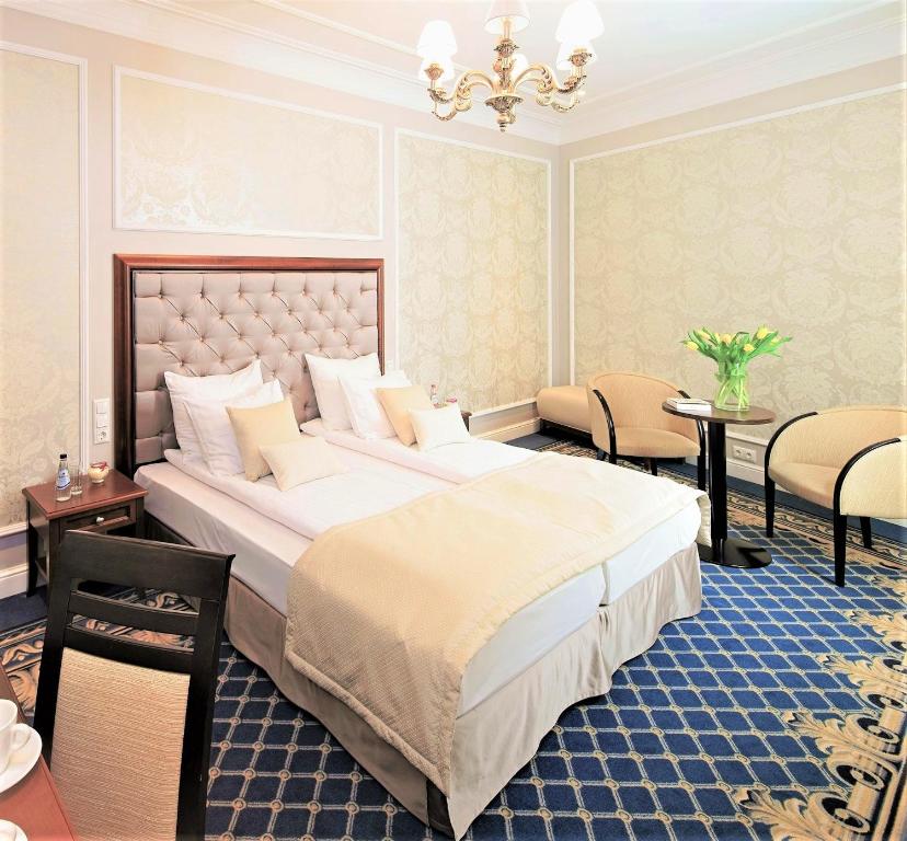 a bedroom with a large bed and a table and chairs at Rixwell Gertrude Hotel in Riga