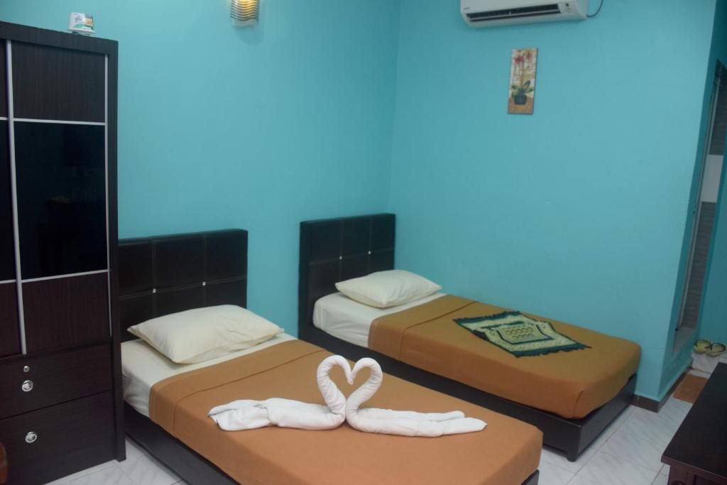 two beds with towels on them in a room at HOTEL RAUDHAH Kerteh in Kertih