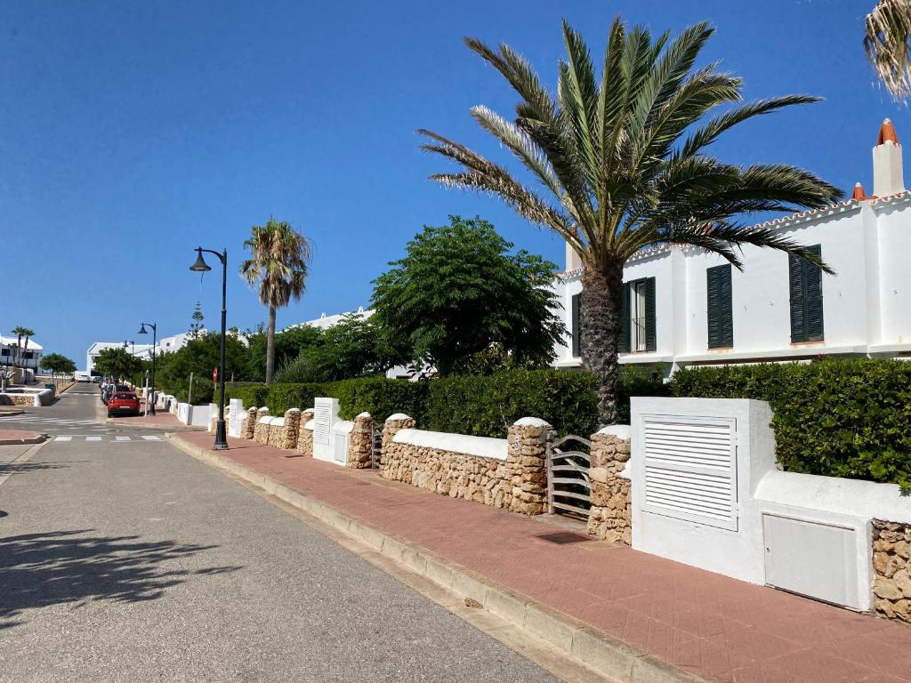 eine Straße mit einem weißen Zaun und einer Palme in der Unterkunft ES BERRY 3 by SOM Menorca in Fornells
