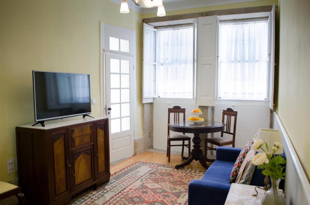 sala de estar con TV y sofá azul en Porto.arte downtown apartment, en Oporto