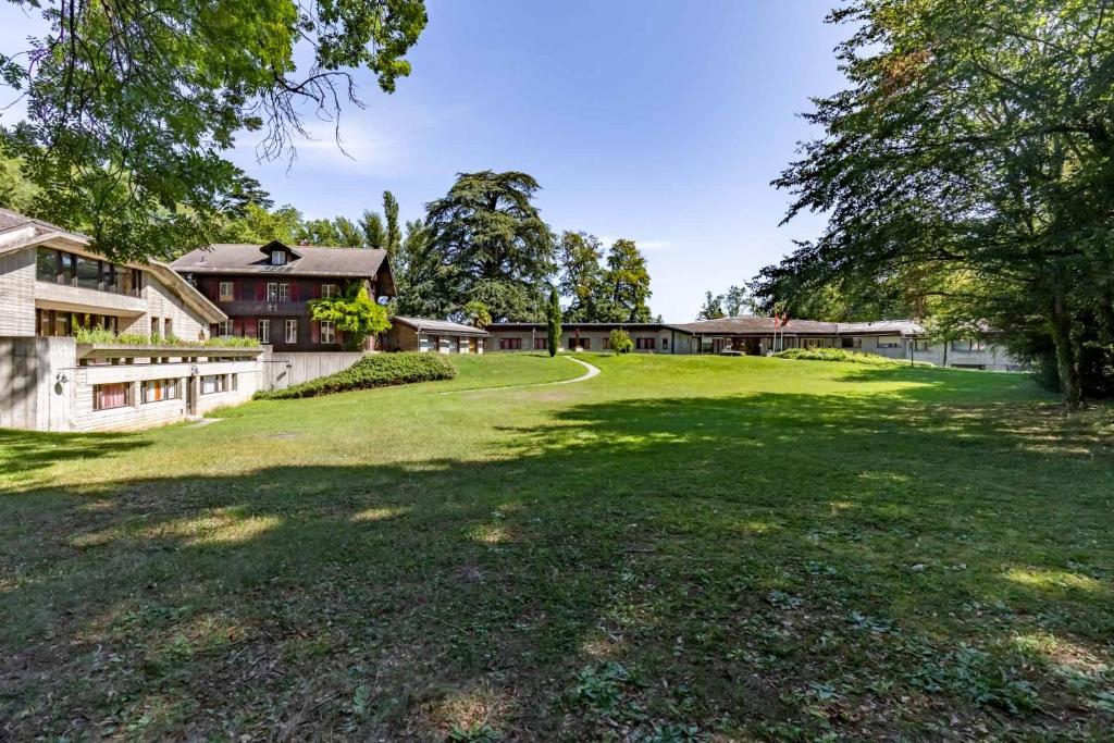 einen großen grünen Hof mit einem Haus und Bäumen in der Unterkunft John Knox International Center in Genf