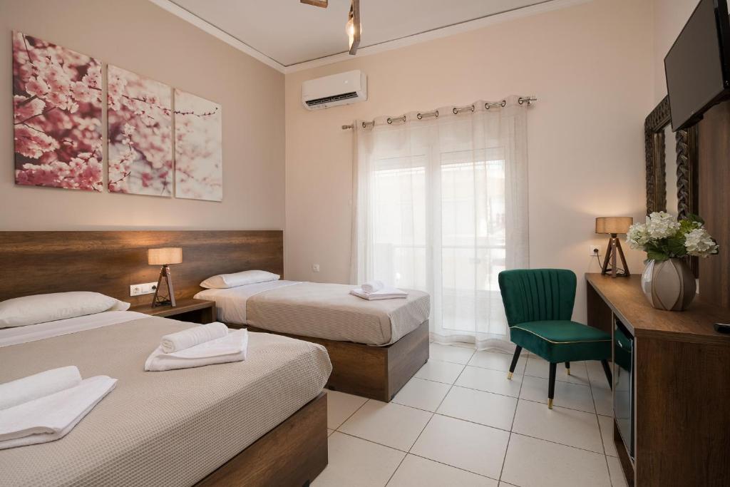 una habitación de hotel con 2 camas y una silla en Olympic Hotel, en Moírai