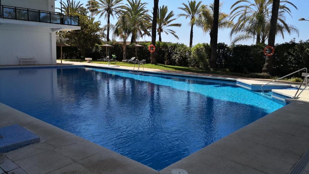 una gran piscina azul con palmeras en el fondo en Skol 837B by Completely Marbella, en Marbella