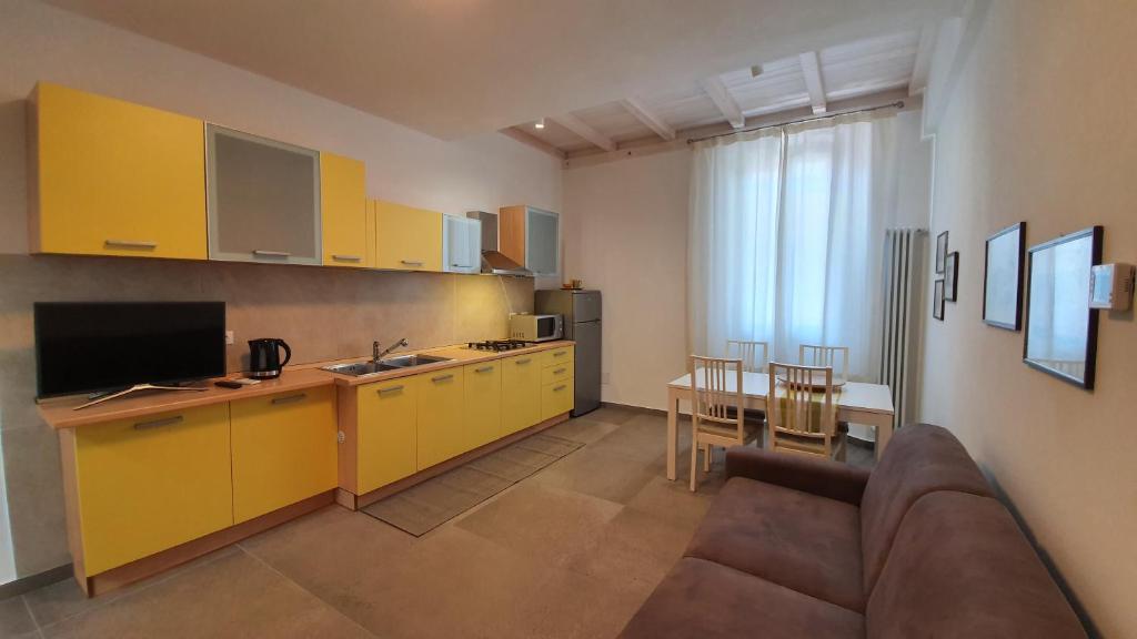 une cuisine avec des armoires jaunes et un canapé dans une pièce dans l'établissement RomagnaBNB Dal Mazareta, à Forlimpopoli