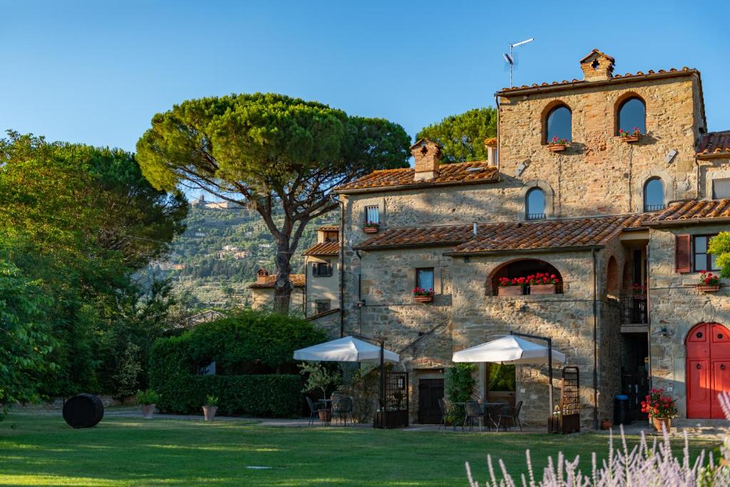 Cette grande maison en pierre est dotée d'une porte rouge. dans l'établissement Monastero San Silvestro, à Cortone