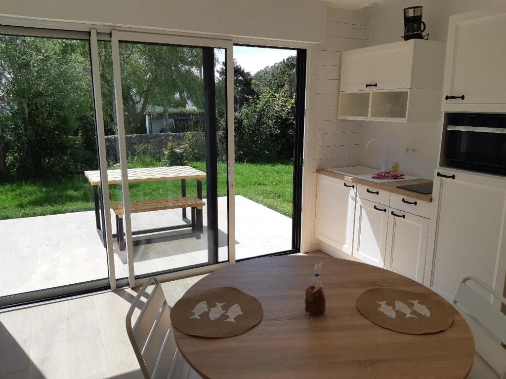a kitchen with a table and a large sliding glass door at ETABLISSEMENT CHEZ JULES in Ambleteuse