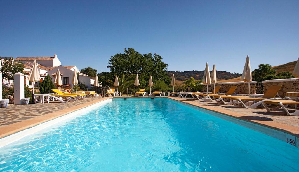 una gran piscina con sillas y sombrillas en Hotel Cortijo Las Piletas, en Ronda