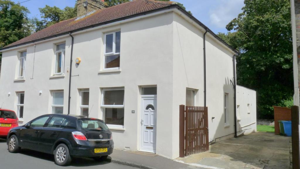 a white house with a car parked in front of it at Bassett House with 3 bedrooms, fast Wi-Fi and off road parking in Kent