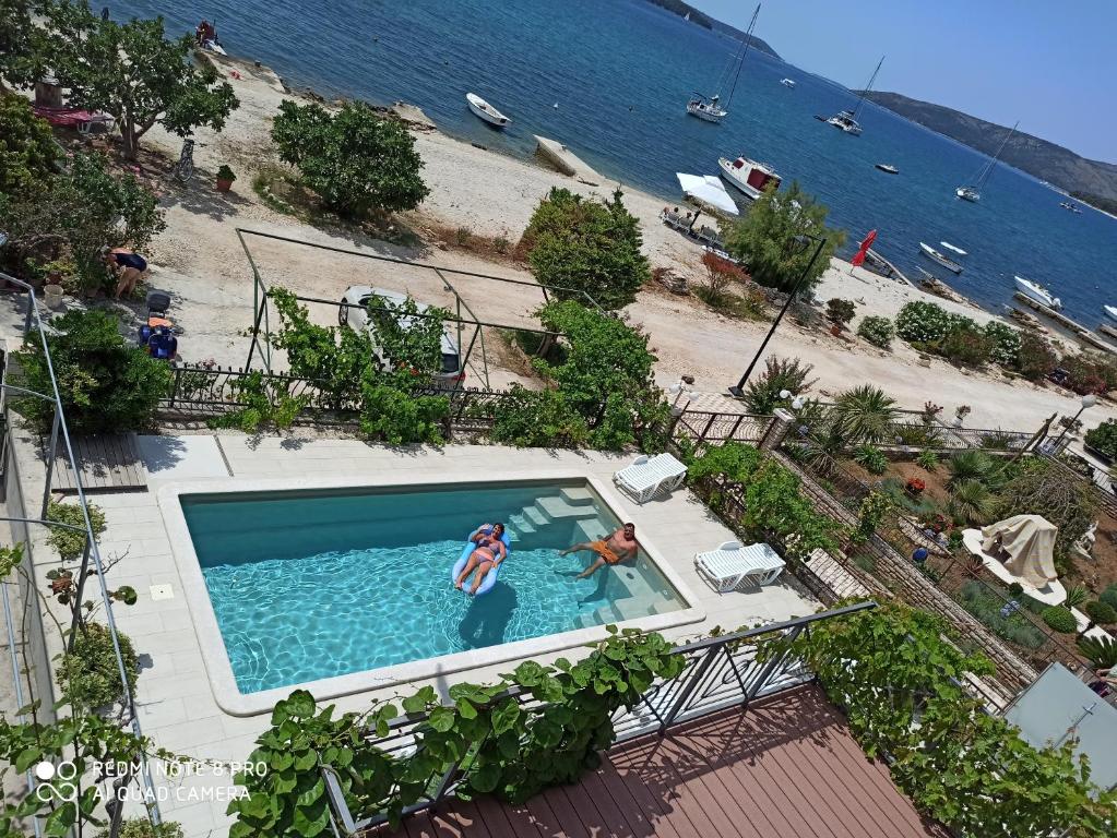 two people in a swimming pool next to a beach at Apartments Gina in Trogir