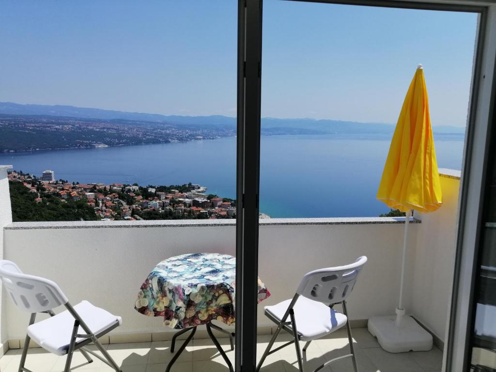 a table and chairs on a balcony with a view of the water at Apartmani Irena in Veprinac