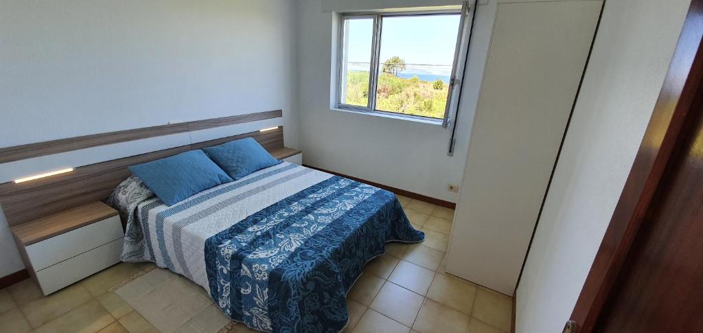 a small bedroom with a bed and a window at Carnota PLAYA a 100 metros in Carnota