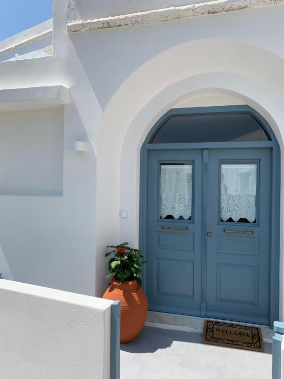 a blue door in a white building with a plant at Captain's House Plaka Milos in Plaka Milou