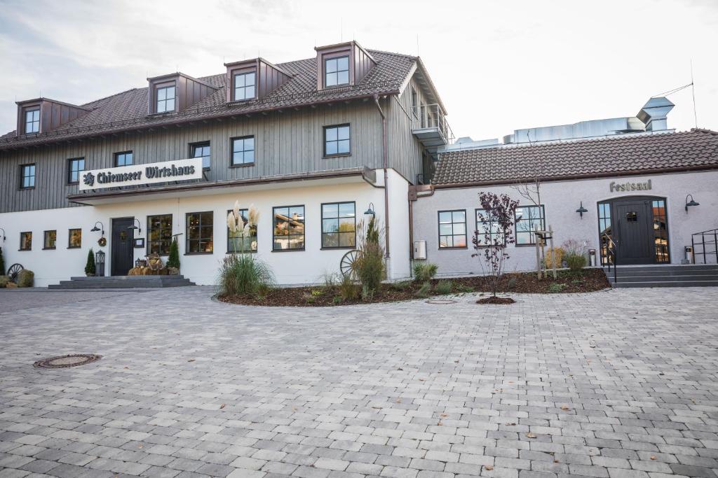 - un grand bâtiment blanc avec une allée devant dans l'établissement Chiemseer Wirtshaus, à Chieming