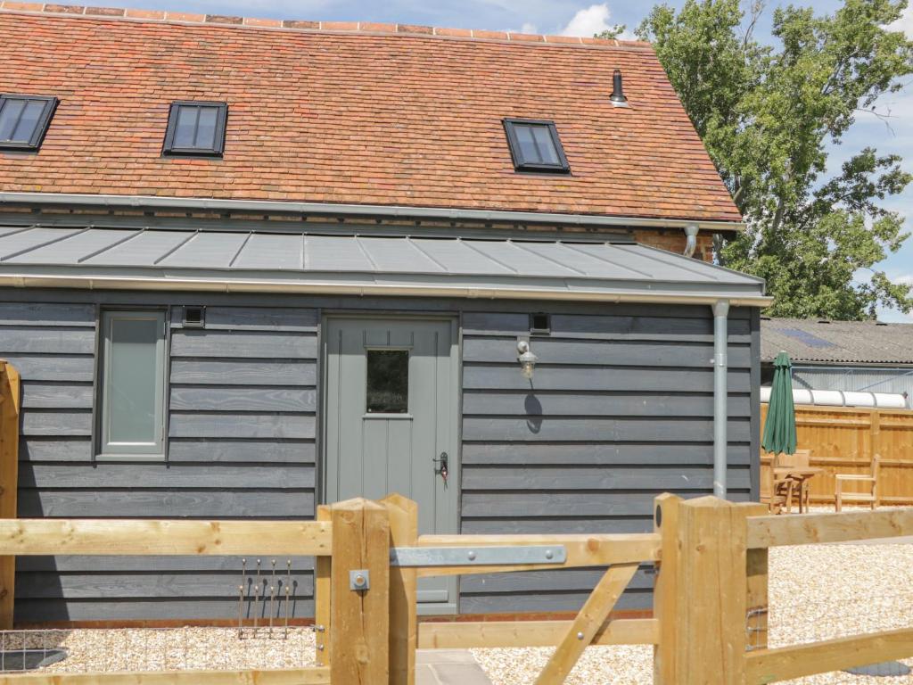 una pequeña casa gris con una valla de madera en Kingfisher, 2 The Old Stables, en Witney