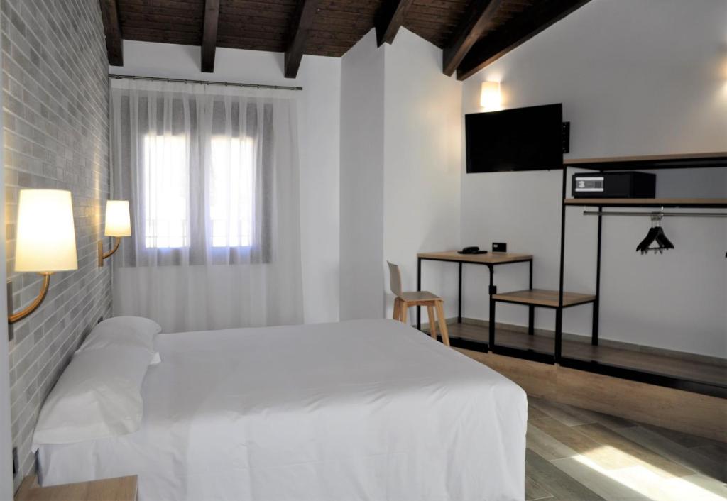 Dormitorio blanco con cama blanca y TV en Hostal Restaurante Villa de Brihuega, en Brihuega