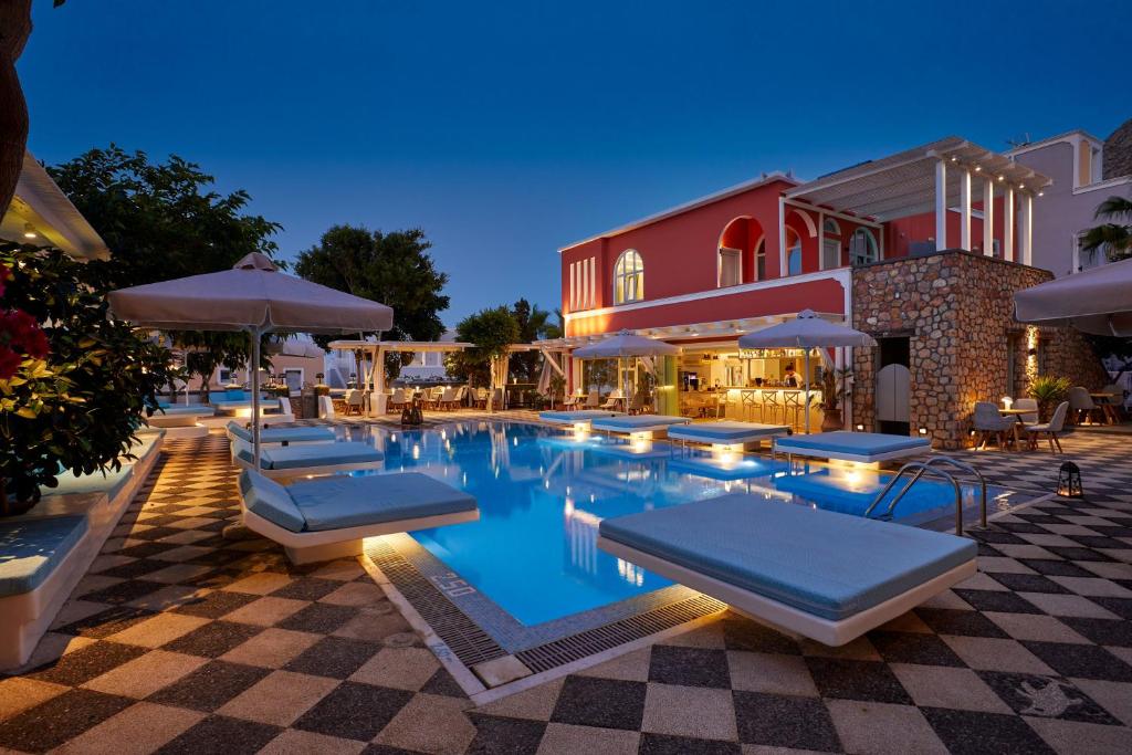 a swimming pool with lounge chairs and umbrellas next to a building at Blue Sea Hotel in Kamari