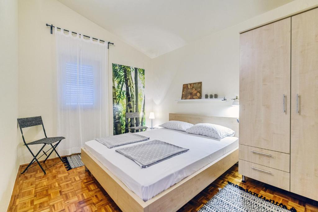 ein weißes Schlafzimmer mit einem großen Bett und einem Fenster in der Unterkunft Apartman Veronika Zadar in Zadar