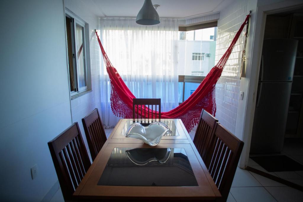 ein Esszimmer mit einem Tisch, Stühlen und roten Vorhängen in der Unterkunft Suíte Guarapari - 3 quartos na Praia das Virtudes in Guarapari