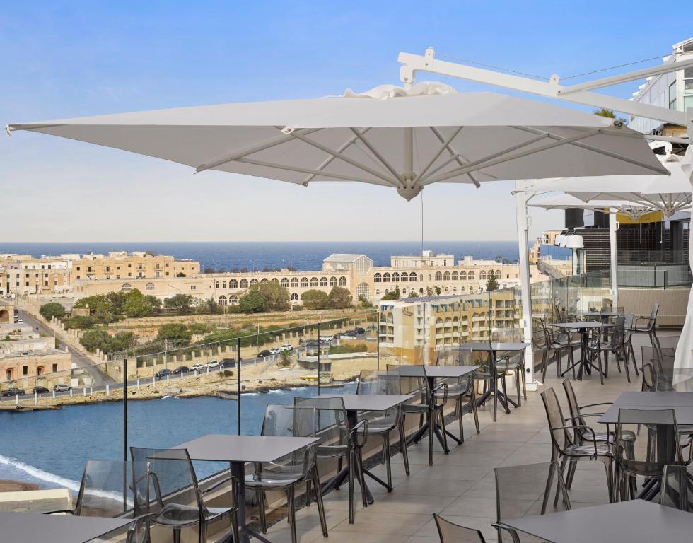 a group of tables with umbrellas on a roof at Holiday Inn Express - Malta by IHG in St. Julianʼs
