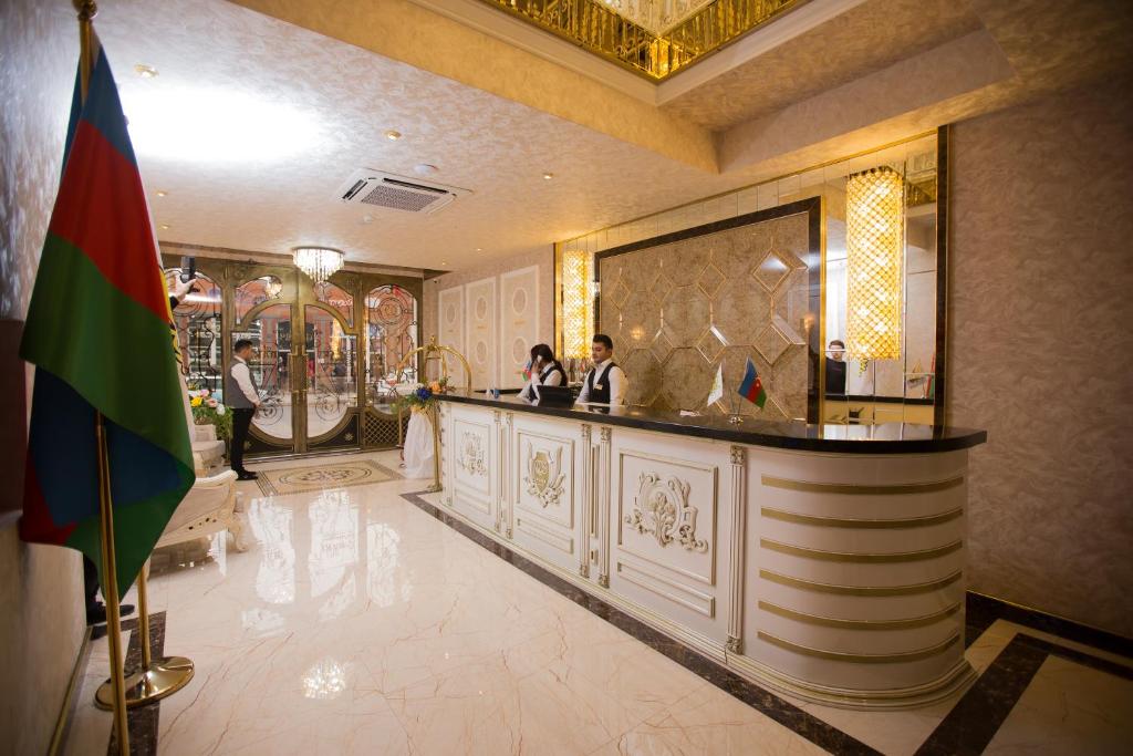 a lobby of a hotel with two people standing at a bar at Baku Hotel Ganja in Ganja