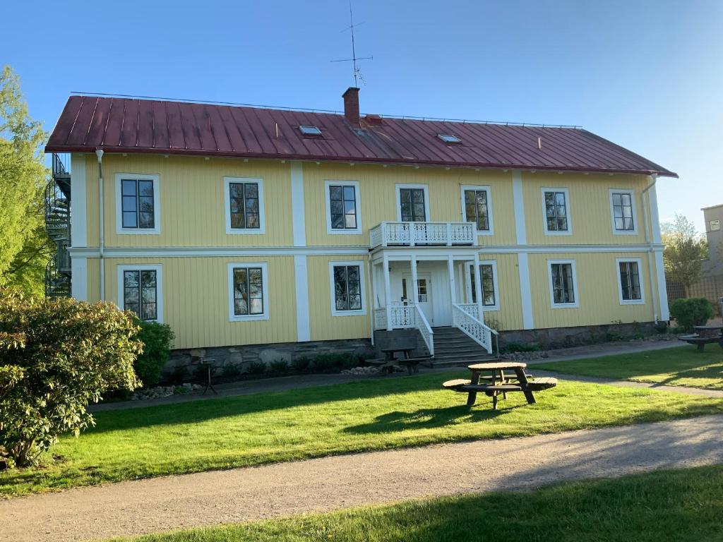 una casa amarilla con una mesa de picnic delante de ella en Evedals Vandrarhem Växjö en Växjö