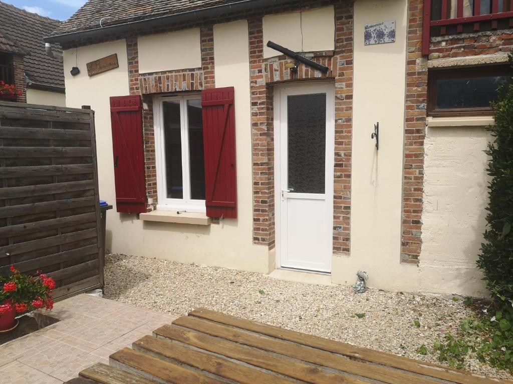 a house with red shutters and a white door at Maisonnette La Bienvenue in Trainel