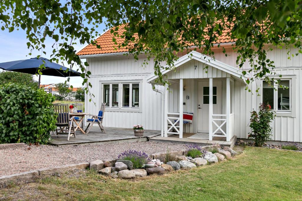 uma casa branca com uma mesa e cadeiras e um guarda-sol em Villa Tjurpannan Grebbestad em Grebbestad