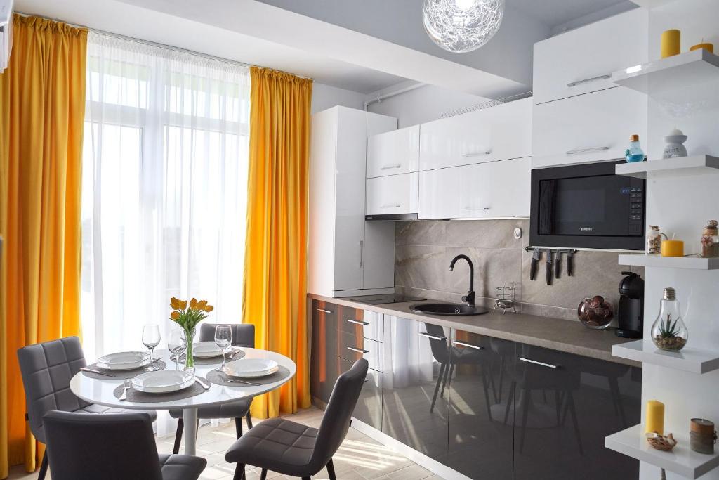 una cocina con mesa y sillas y una cocina con cortinas amarillas. en Aba Luxury Studio Spa n Pool Beach resort en Mamaia-Sat