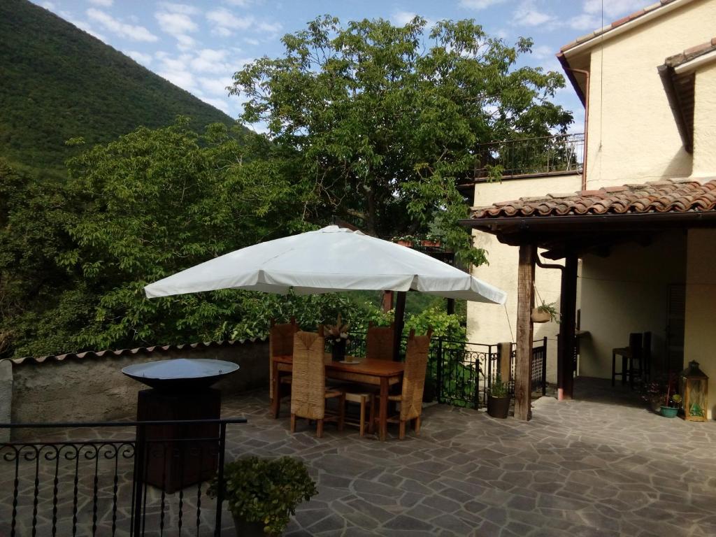 um pátio com uma mesa e um guarda-chuva em Bed & Breakfast SENTIERO 54 em Cantiano