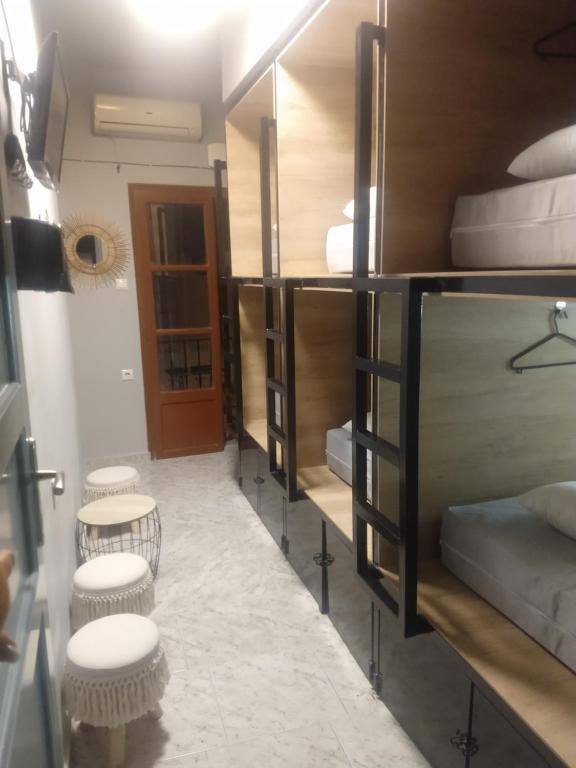 a room with a row of bunk beds with stools at Boho City Hostel in Chania