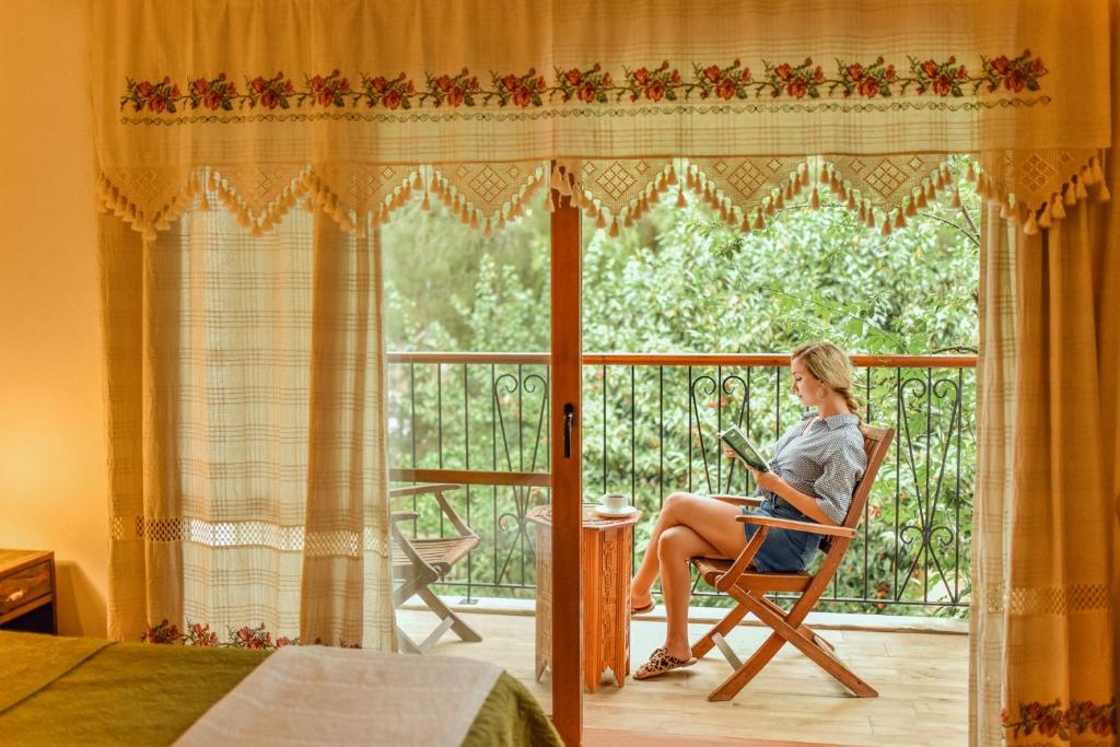 a woman sitting in a chair on a balcony at Pyramid Boutique Hotel in Kayakoy