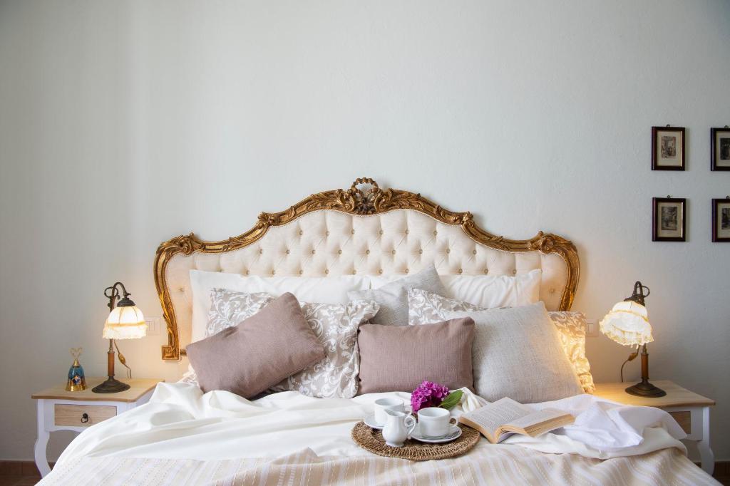 Scacciapensieri Guest House في أريتسو: غرفة نوم بسرير ابيض ومصبغتين وصينية عليها كتب