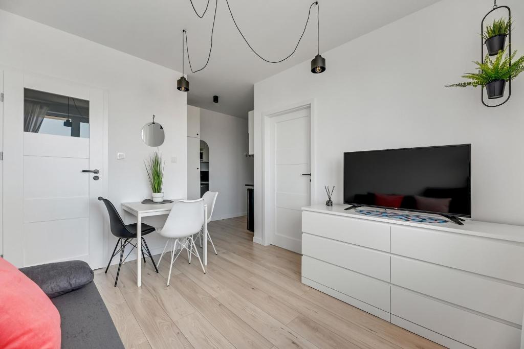 a white living room with a table and a tv at Apartamenty Świętej Barbary in Gdańsk