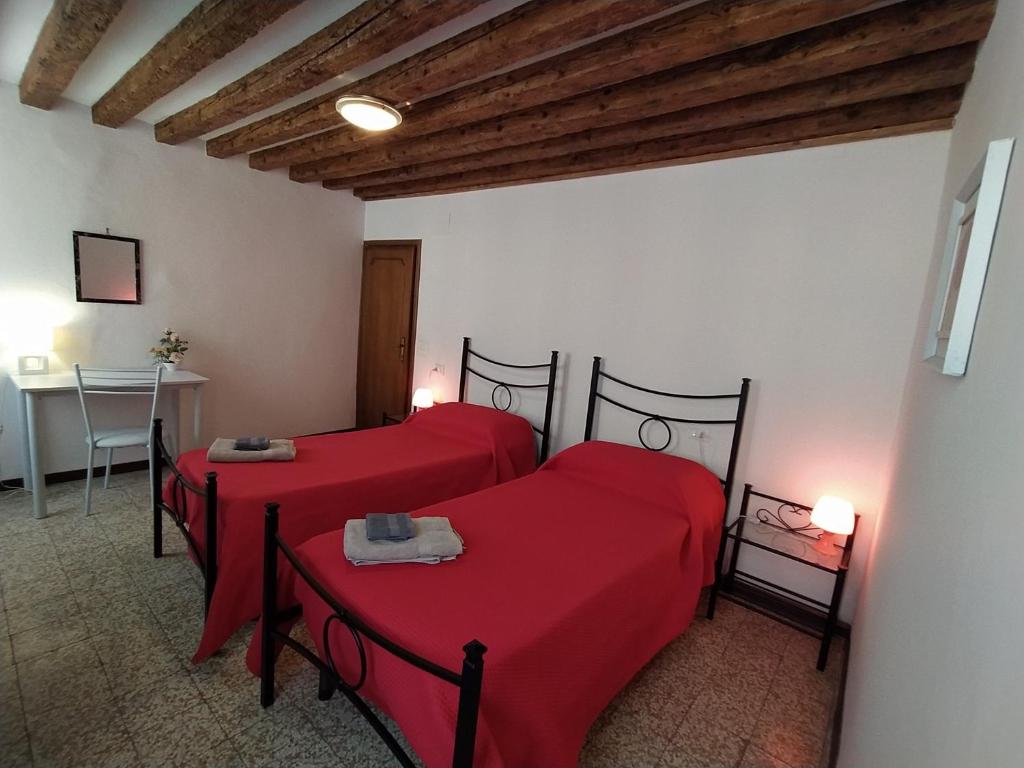 two beds in a room with red sheets at Da Isabella in Venice