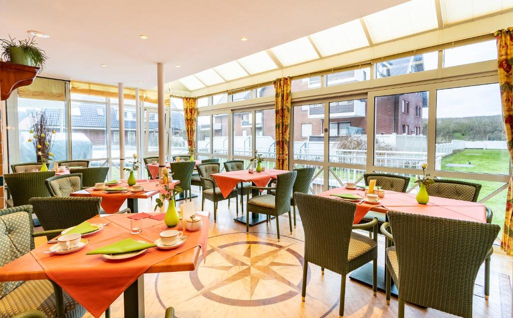 a restaurant with tables and chairs and windows at Strandhotel Sylt Westerland in Westerland