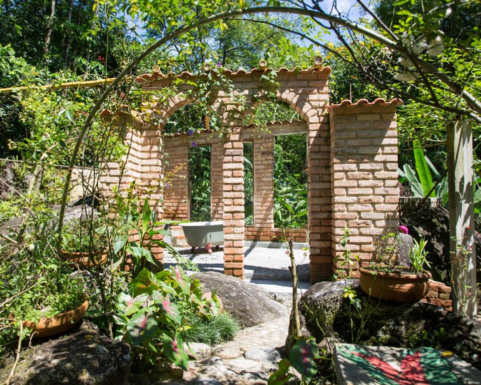 a brick archway in the middle of a garden at Casa D`Irene - Zen Space in Cachoeiras de Macacu