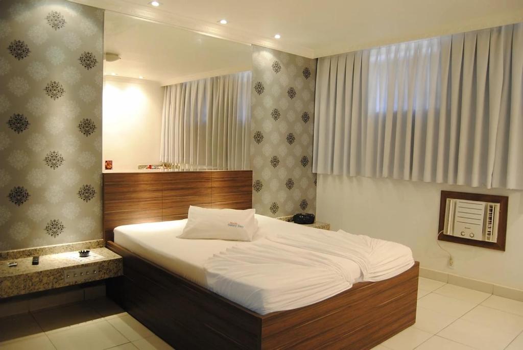 a bedroom with a large bed and a mirror at Motel Sunny Day BH in Belo Horizonte