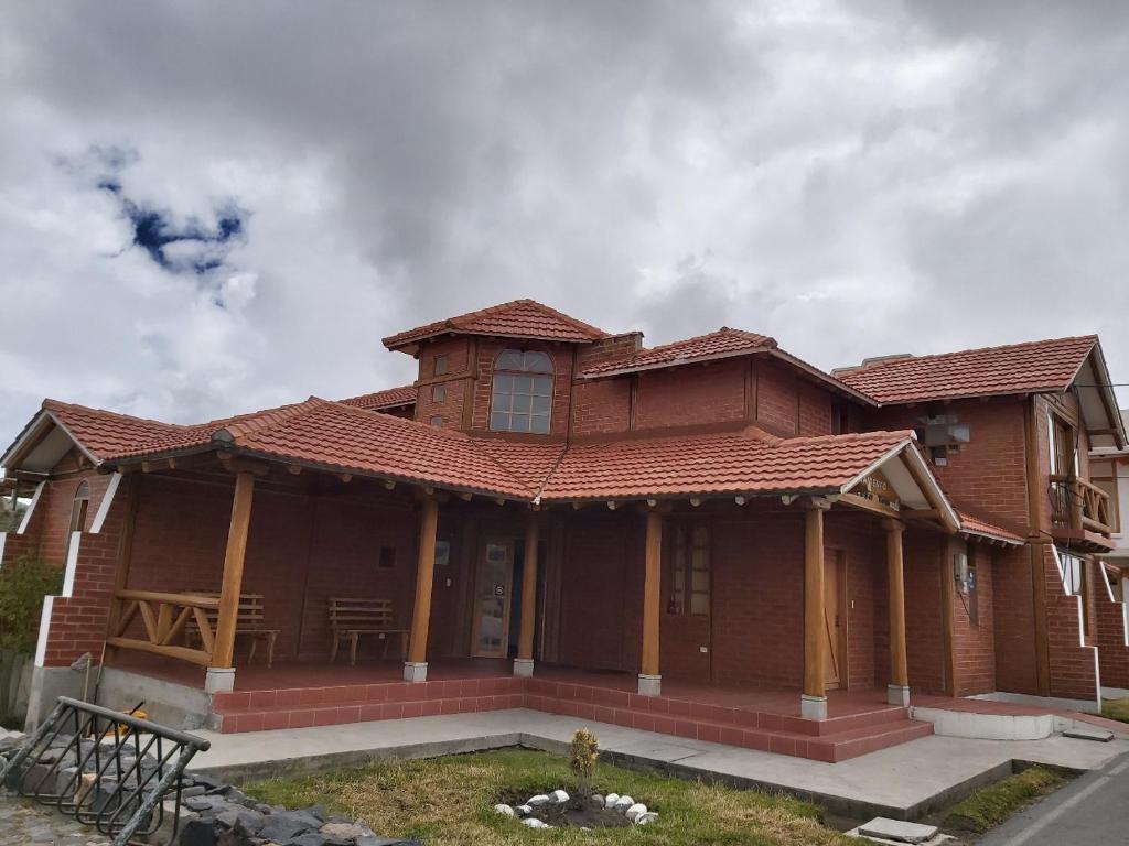 a wooden house with a roof at Hotel PrincesaToa in Quilotoa